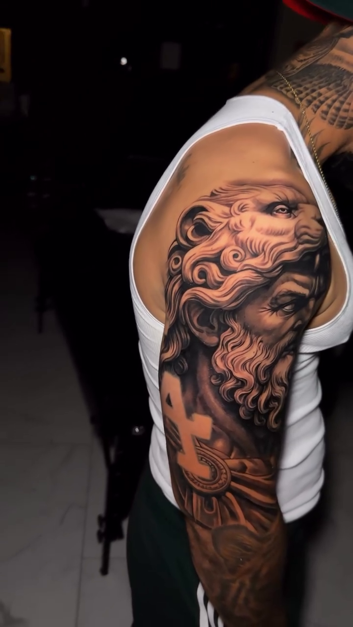 Mythological figure with lion headdress realism tattoo on the upper arm by Flames, Cerritos, California