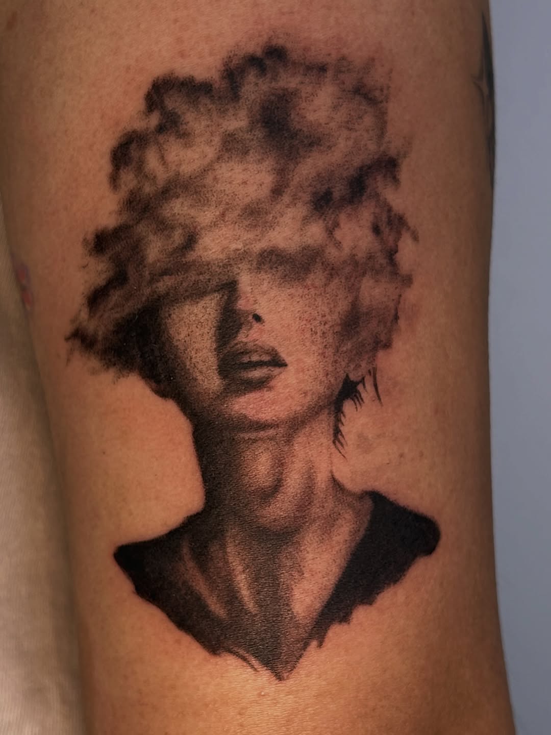 Woman's face dissolving into smoke surrealism tattoo on the forearm by J