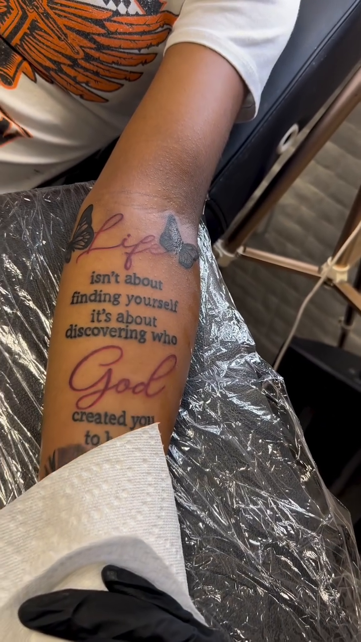 Quote tattoo with floral elements lettering tattoo on the upper arm by Still Standing. Still Creating. 🖤