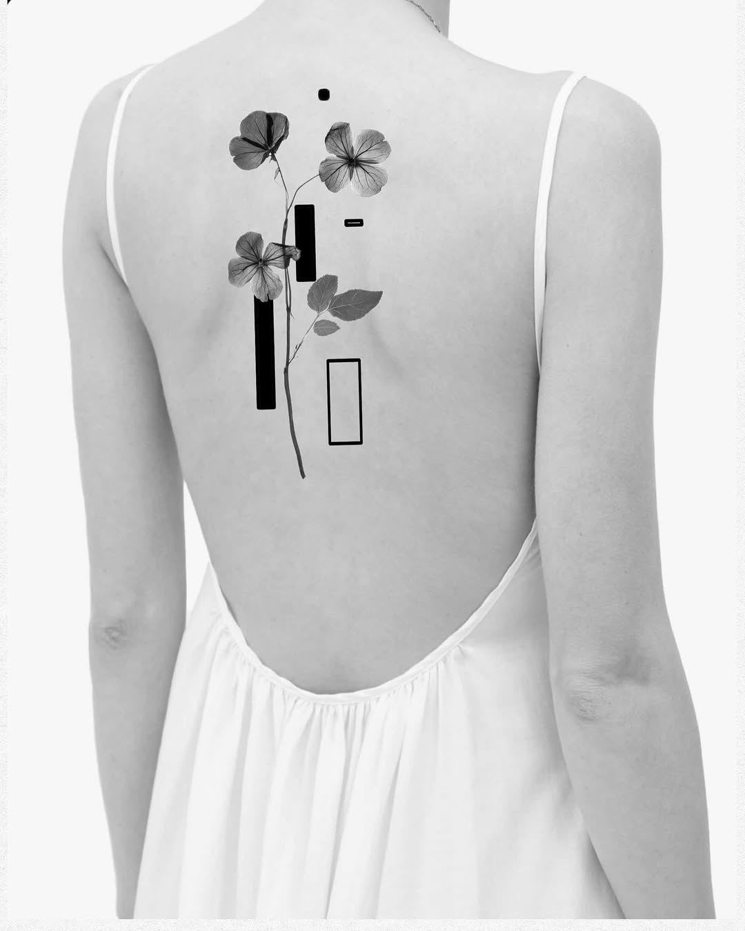 Flower with geometric shapes blackwork tattoo on the back by Xin Huang