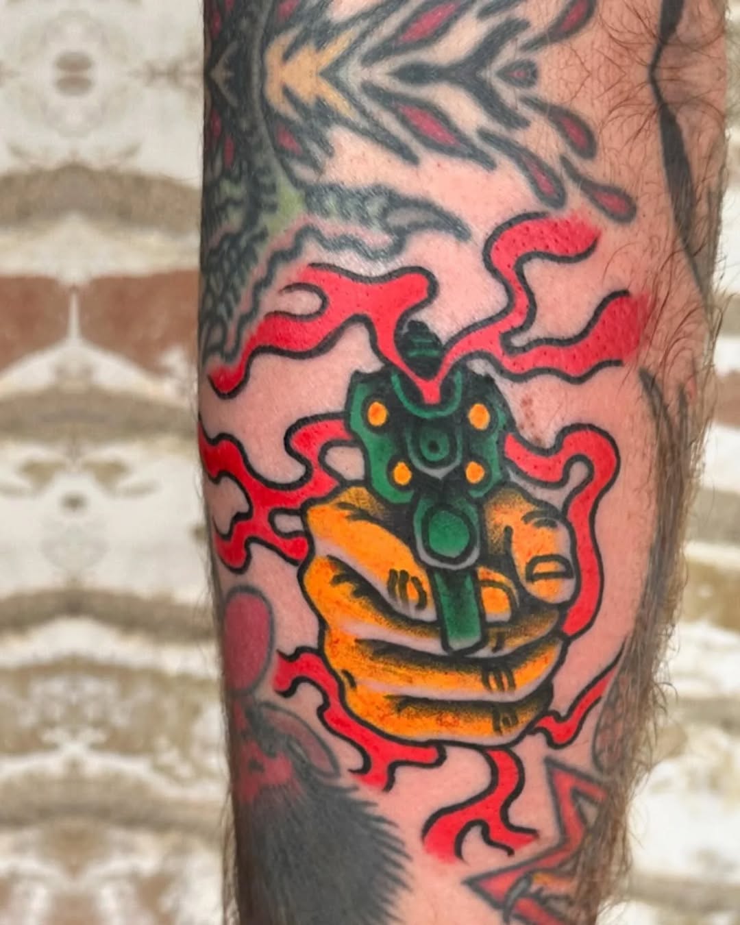 Hand holding a gun American traditional tattoo on the forearm by Jaquelin Miller