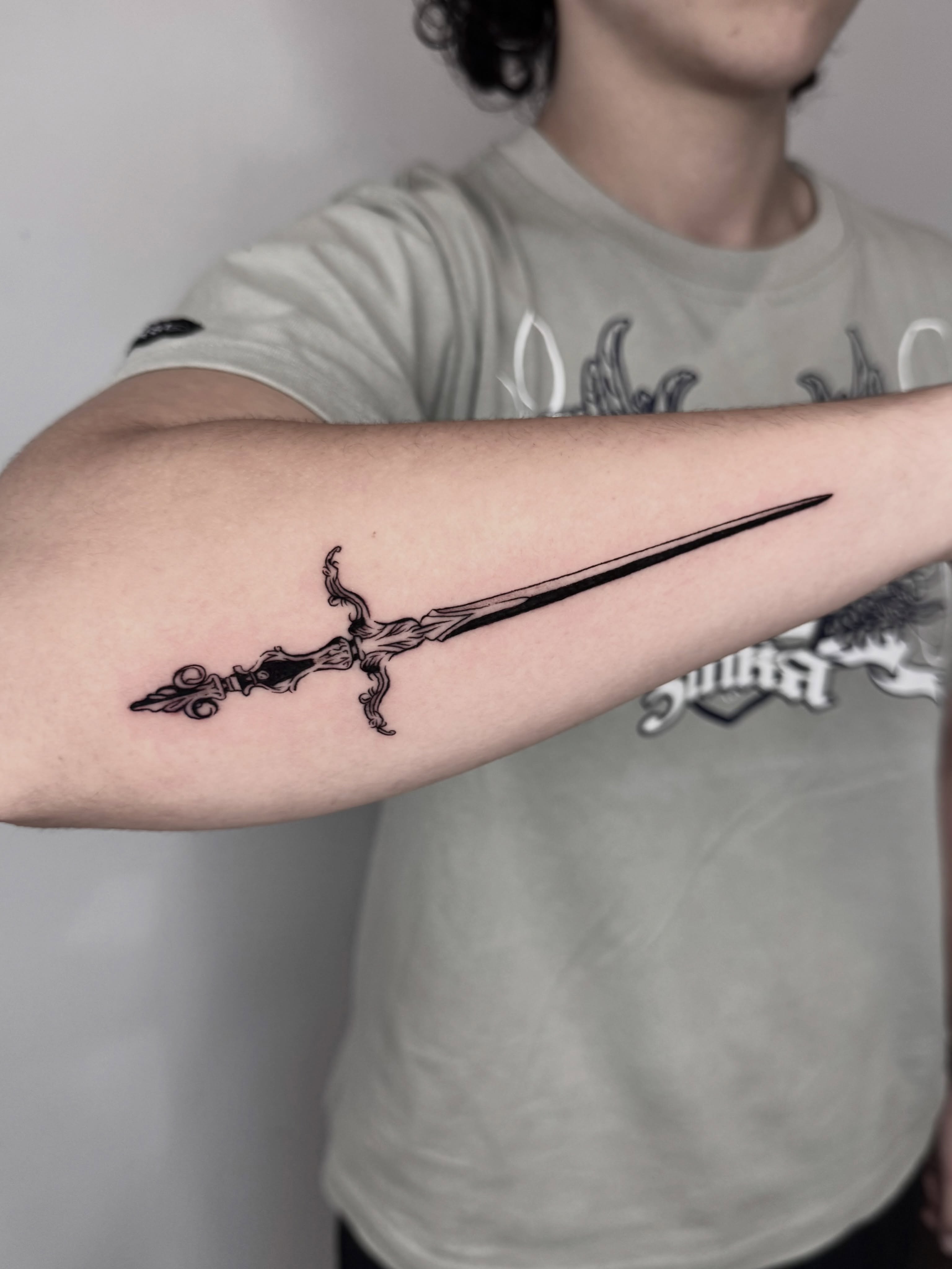 Sword black and grey tattoo on the forearm by Blackwork Vamos