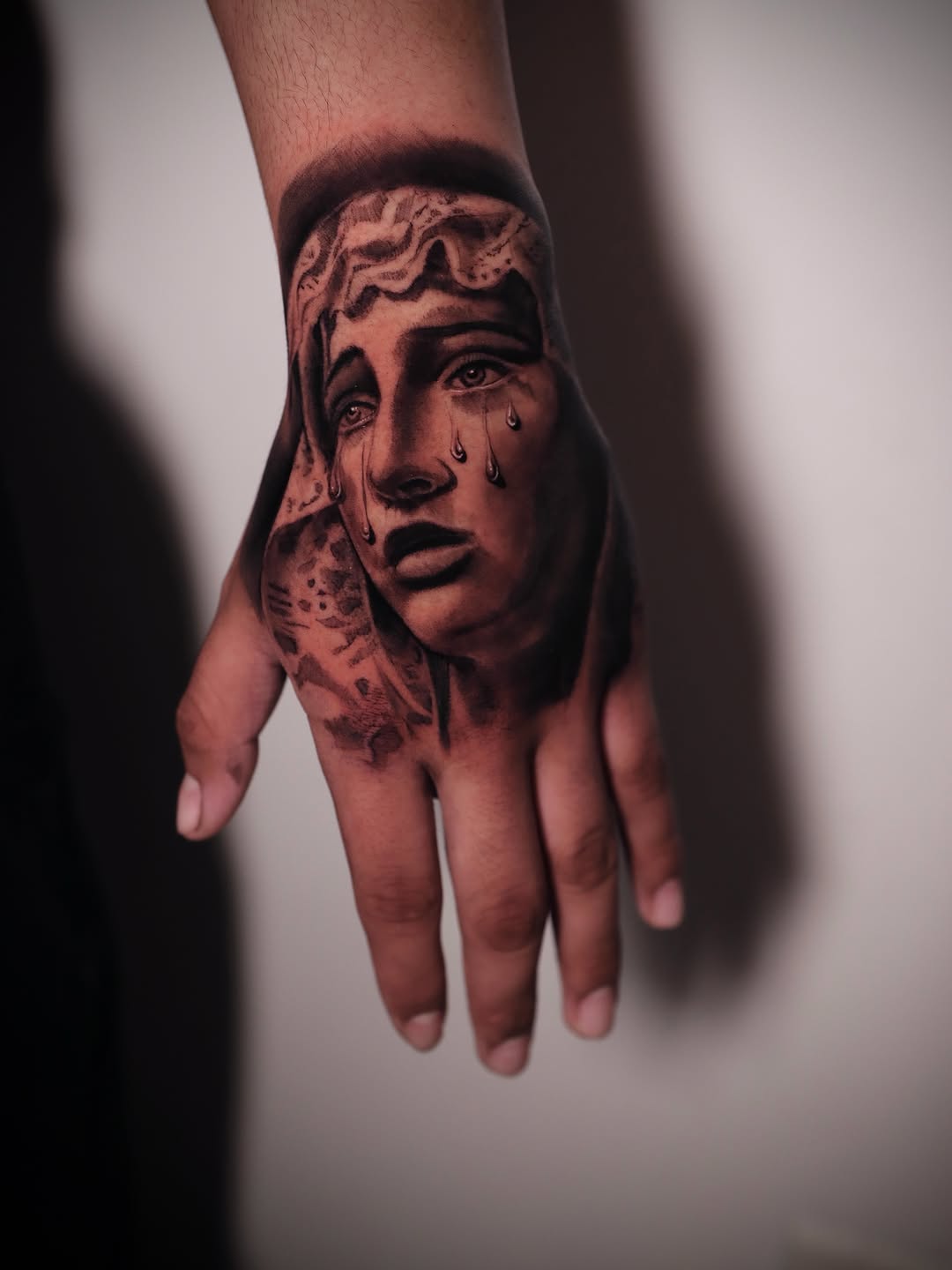 Crying woman's face Chicano tattoo on the hand by elvis flores
