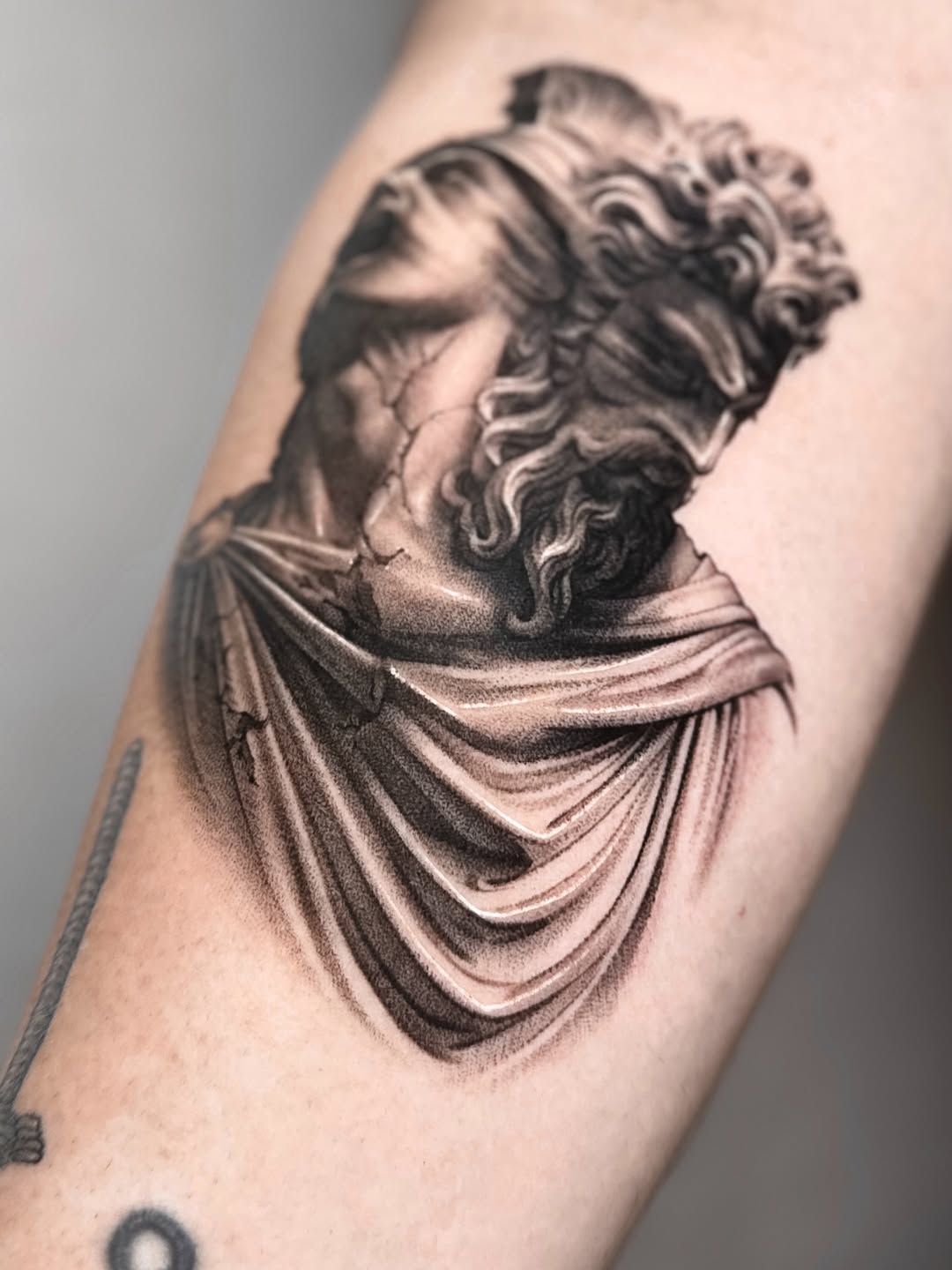 Blindfolded statue head surrealism tattoo on the forearm by Saru