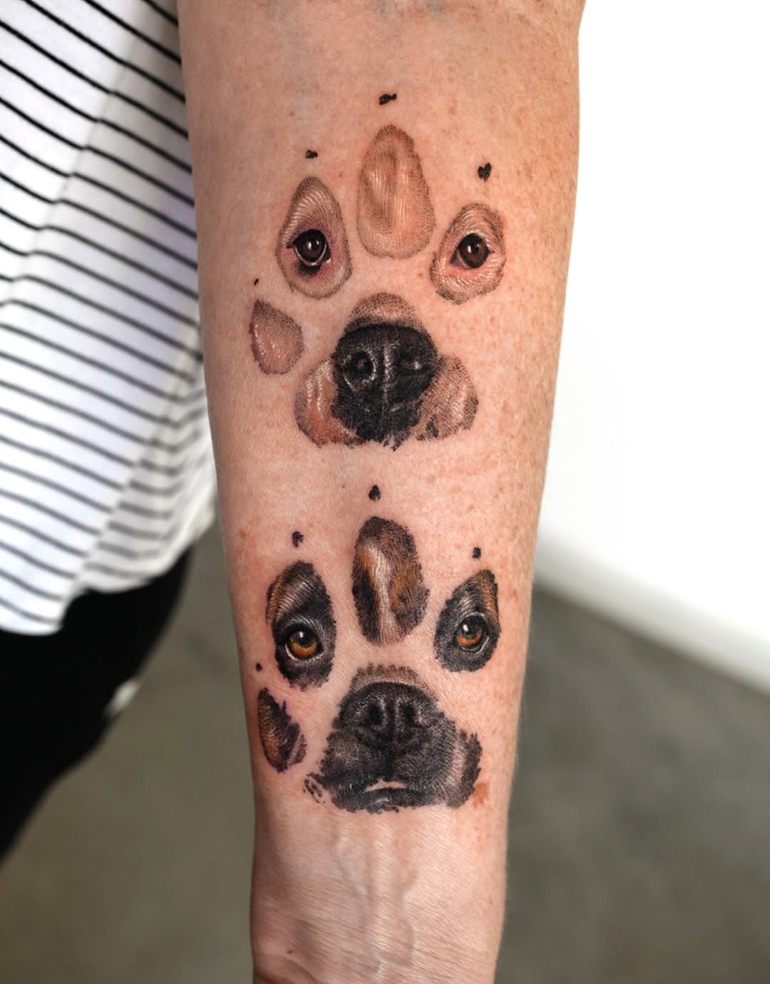 Dog paw prints with faces realism tattoo on the forearm by Ria Kim 김리아