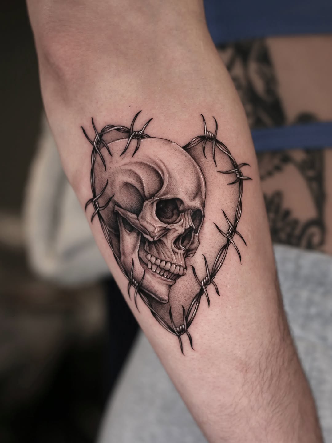 Skull in barbed wire heart dark art tattoo on the forearm by Steve Franciosa