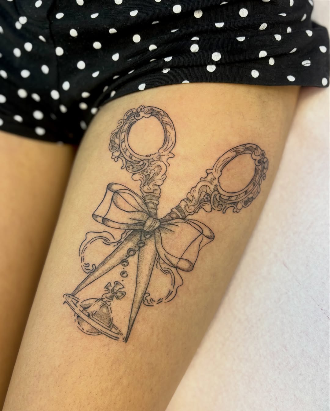 Scissors with bow black and grey tattoo on the thigh by eli (eh-lee)