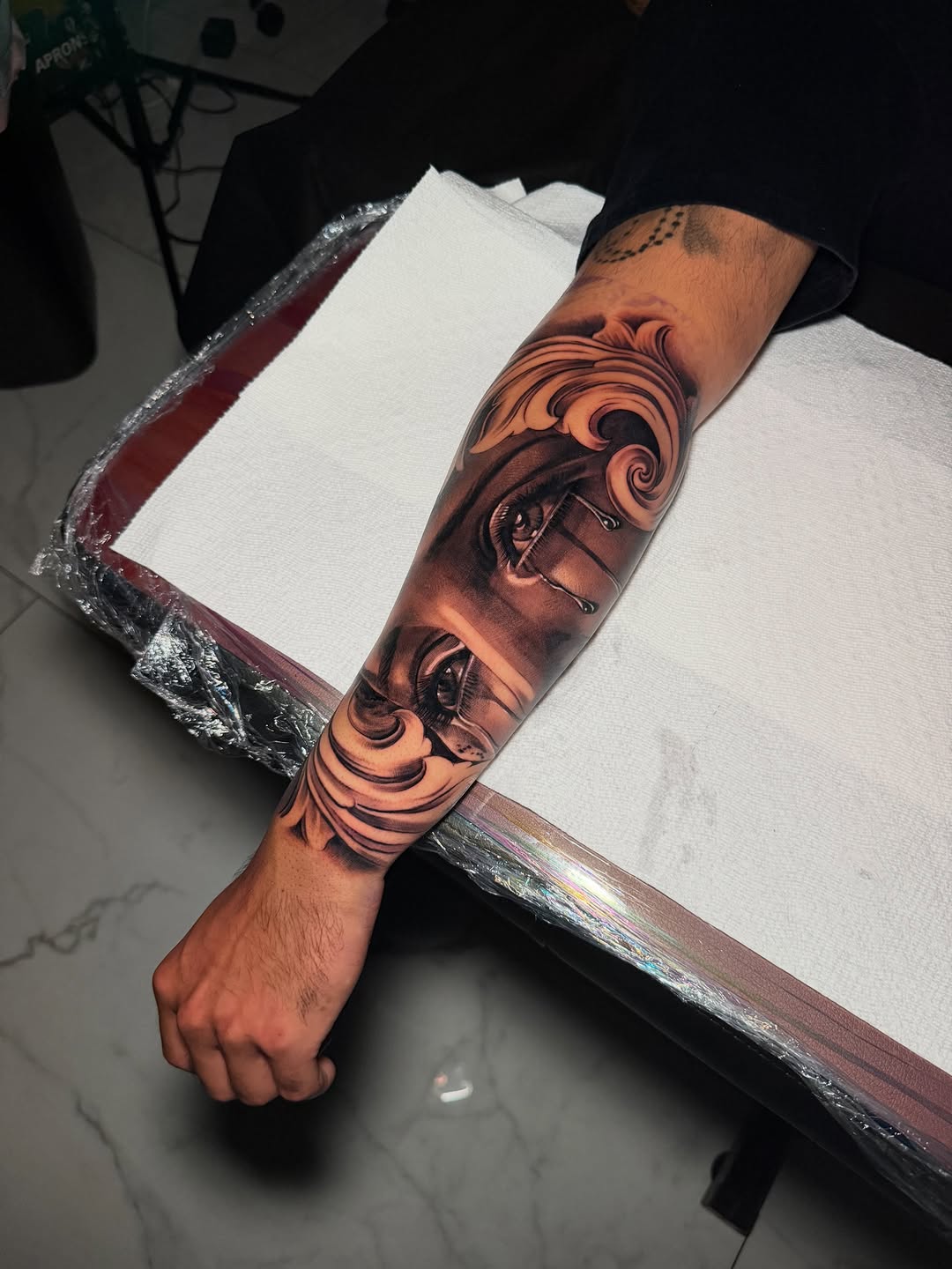 Eye with tears and ornamental scrollwork realism tattoo on the forearm by Flames, Cerritos, California