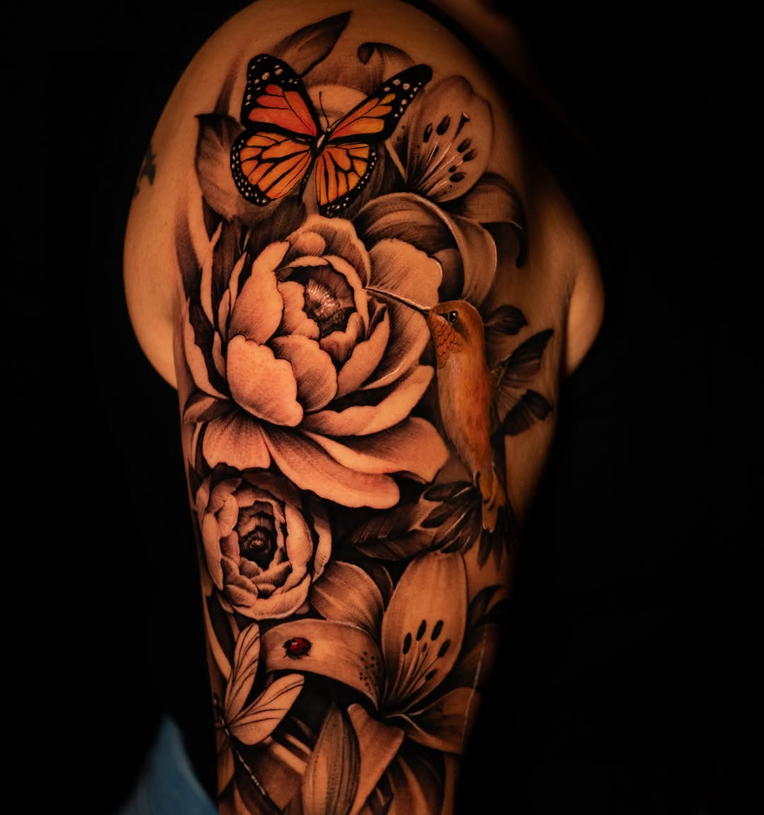 Peonies, lilies, hummingbird, butterfly, and ladybug neo-traditional tattoo on the shoulder by Apolo