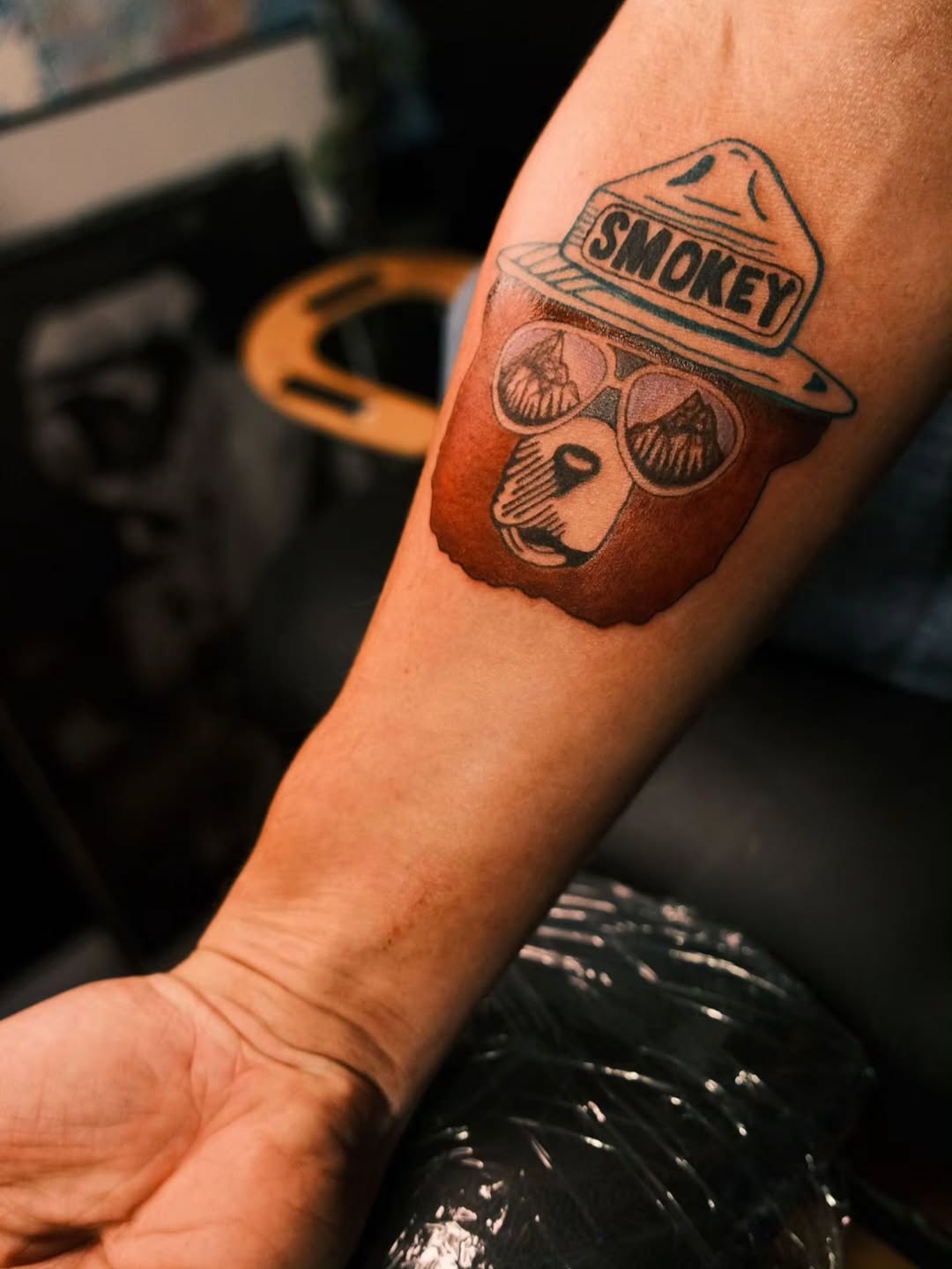 Smokey Bear with sunglasses tattoo on the forearm by Jam ⚡️🐉🖤