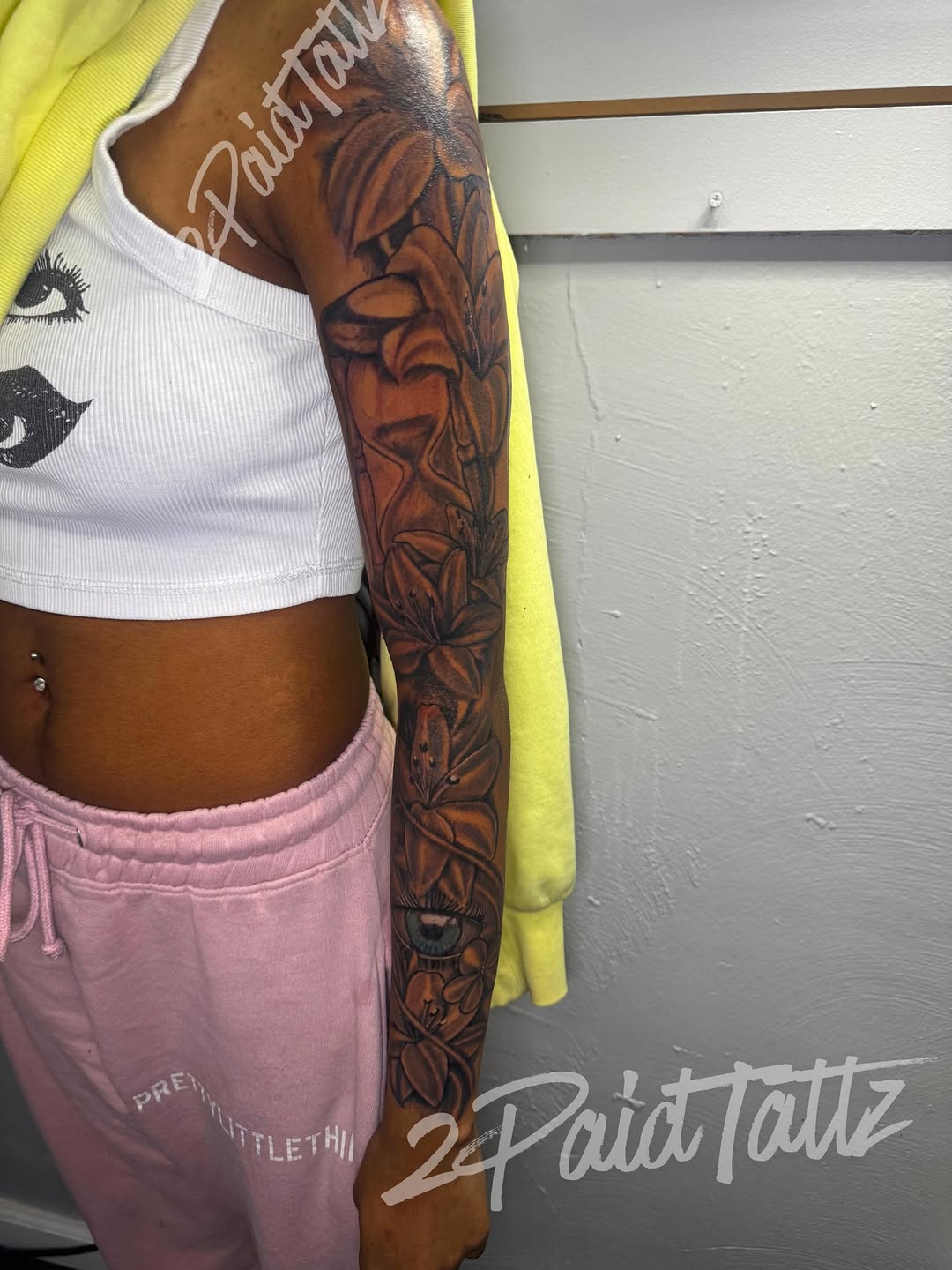 Flowers and eye with hourglass realism tattoo on the forearm by 2PaidTattz