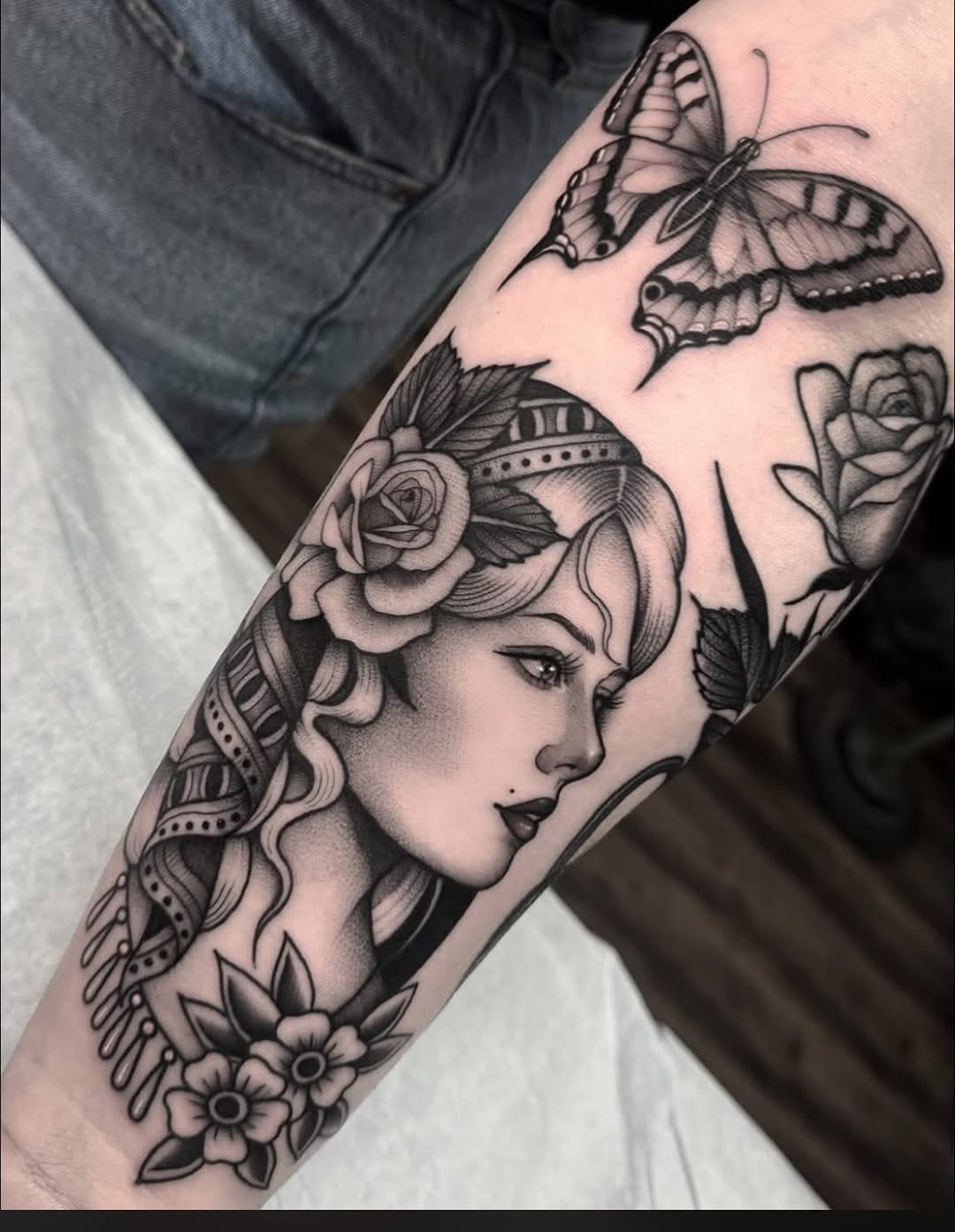 Woman's face with roses and butterfly realism tattoo on the forearm by Luna Lucero