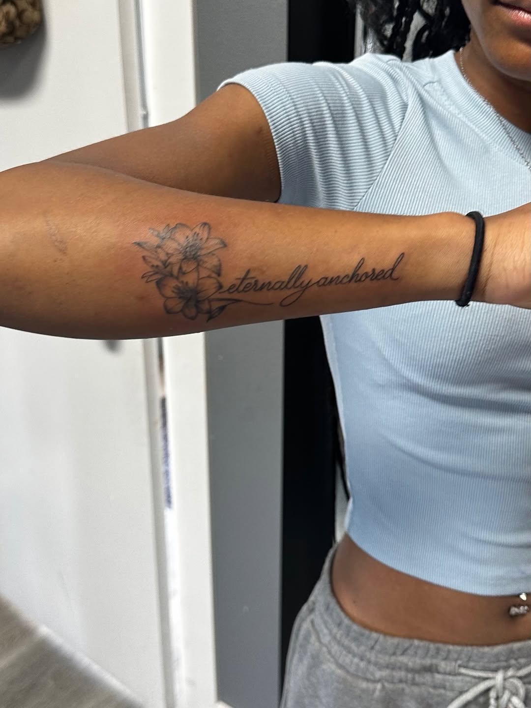 Flowers and script lettering tattoo on the forearm by Lupita Ink