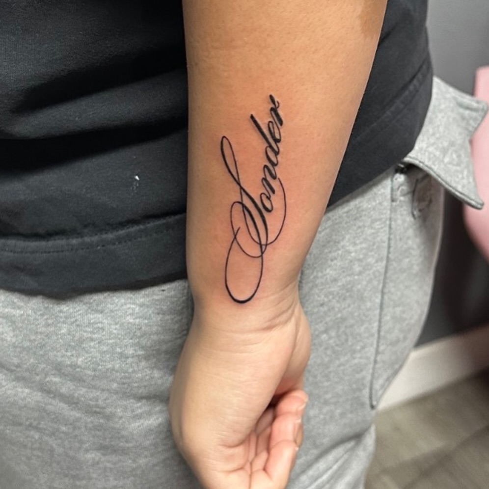 Script lettering lettering tattoo on the forearm by Lupita Ink