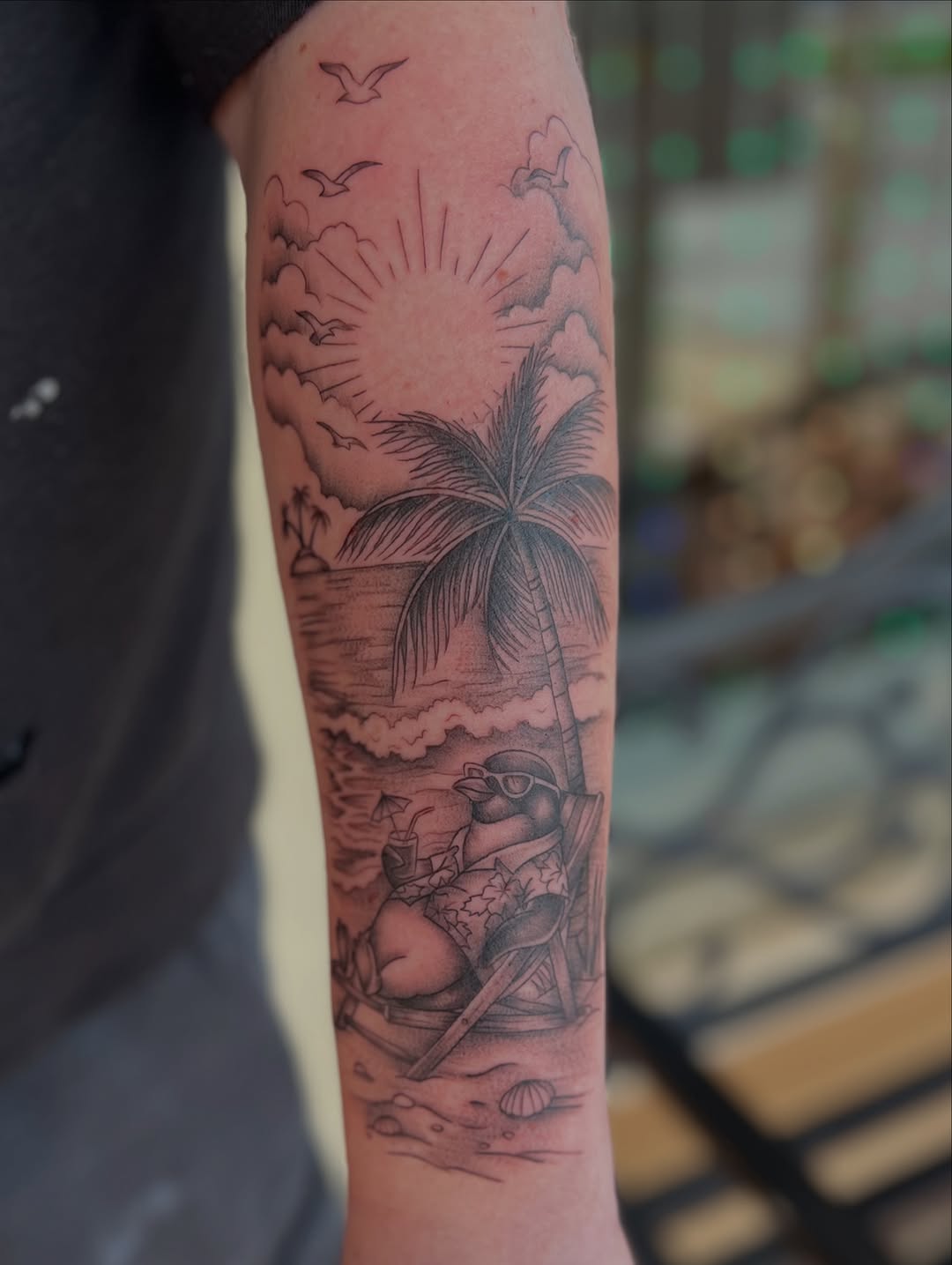 Penguin relaxing on a beach fine line tattoo on the forearm by Jai Woods