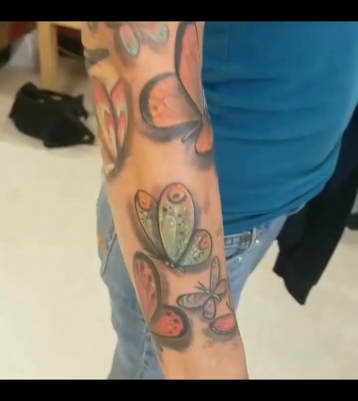 Colorful butterflies on arm watercolor tattoo on the upper arm by Shane Watkins