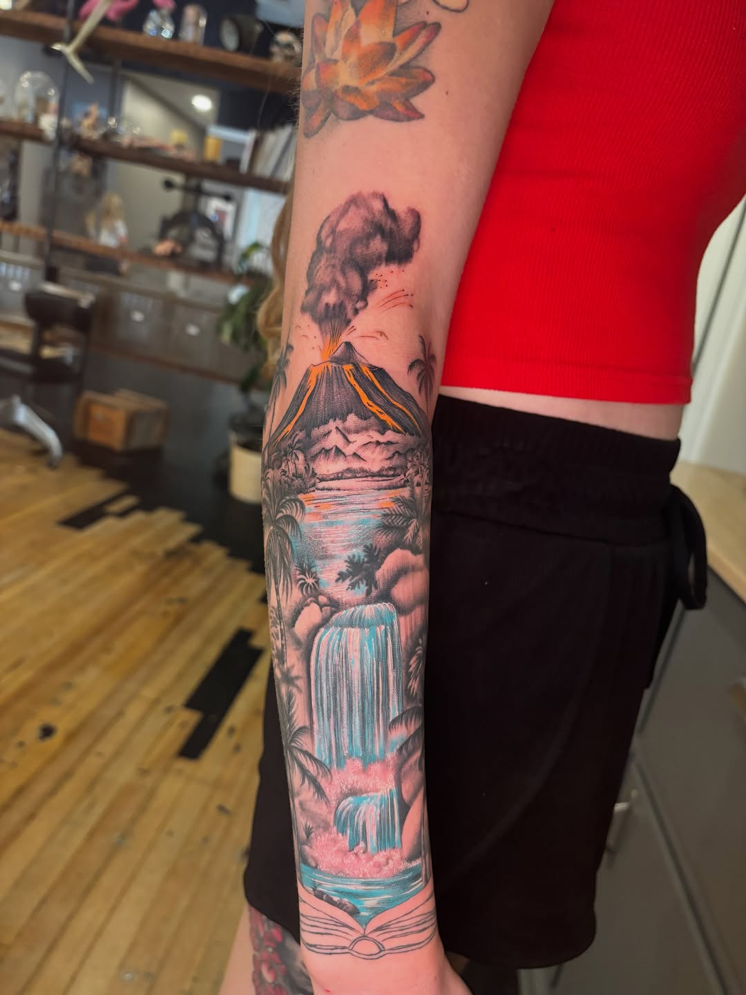 Volcano and waterfall landscape watercolor tattoo on the forearm by Aubri Aunna