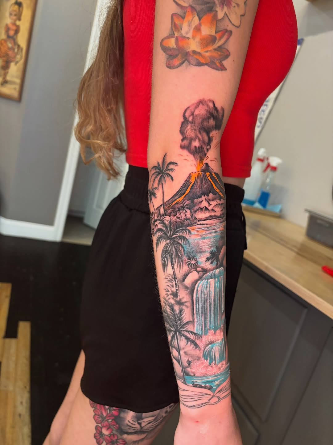 Volcano and waterfall landscape watercolor tattoo on the forearm by Aubri Aunna
