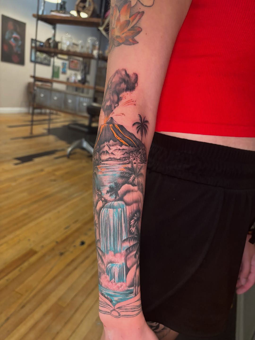 Volcano and waterfall landscape watercolor tattoo on the forearm by Aubri Aunna