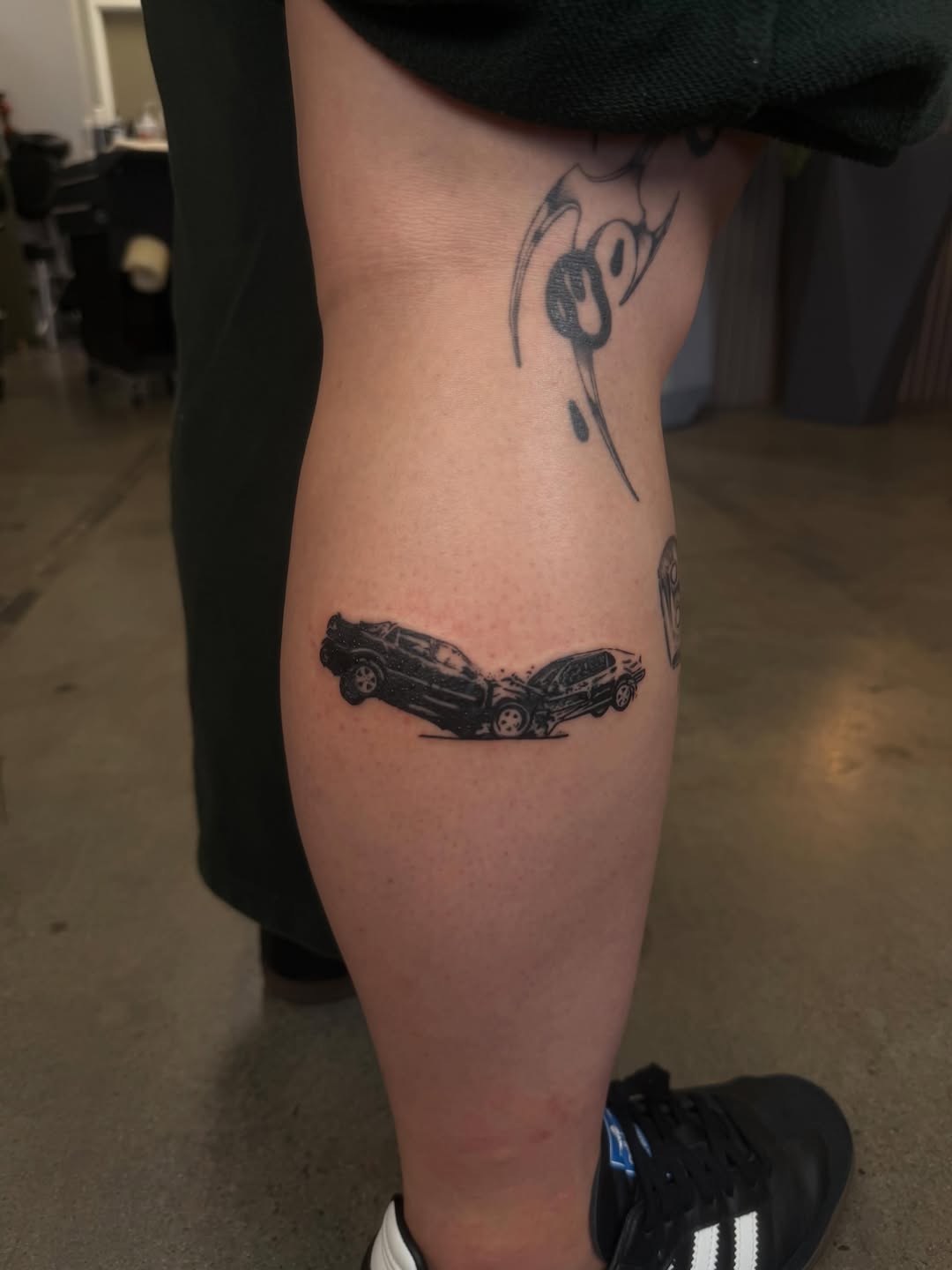Two cars crashing minimalist tattoo on the thigh by Lxx.
