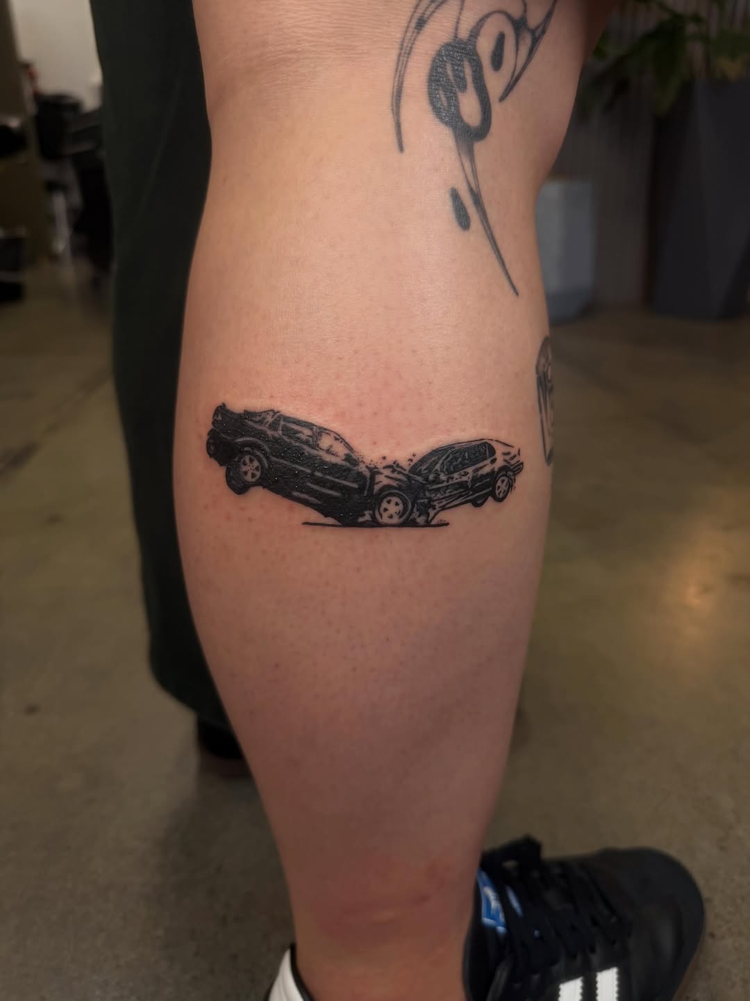 Two cars crashing minimalist tattoo on the thigh by Lxx.