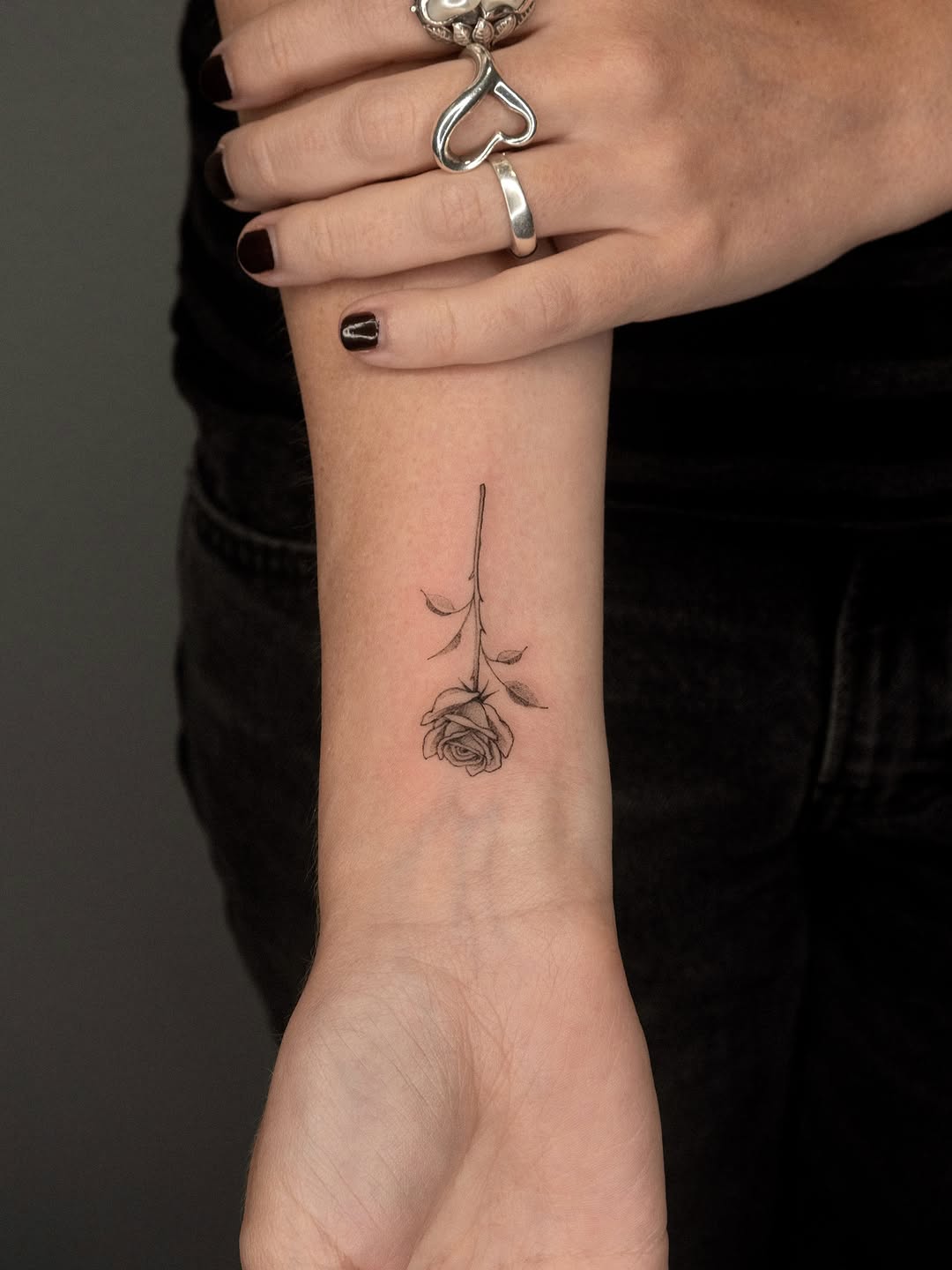 Single rose with stem minimalist tattoo on the forearm by ๐๐๐ฆ ๐๐ ๐ฎ๐ฒ๐๐ง