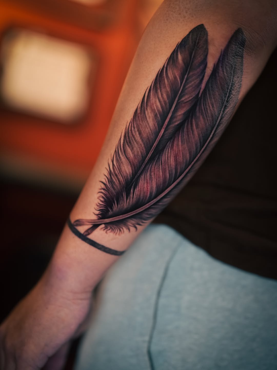 Two feathers fine line tattoo on the forearm by Franz Muñoz