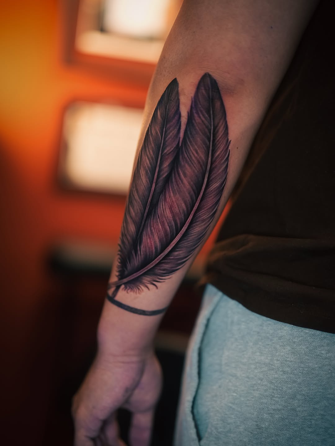 Feathers fine line tattoo on the forearm by Franz Muñoz