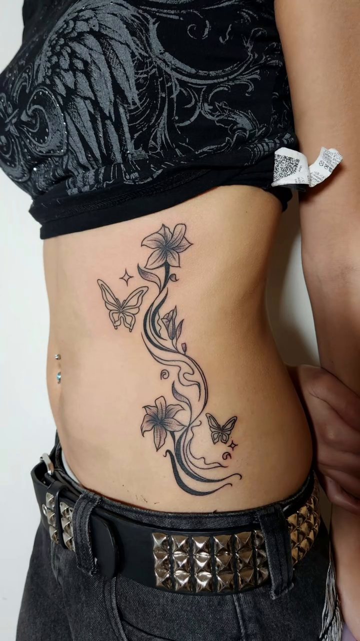 Floral vine with butterflies fine line tattoo on the torso by @youxg_guxxz