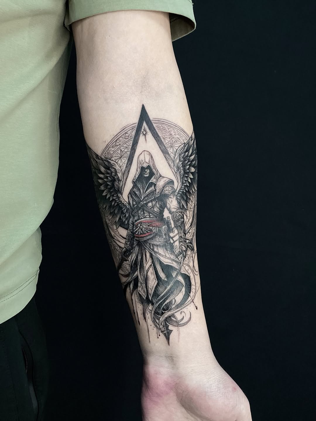 Assassin's Creed character with wings realism tattoo on the forearm by Alexey Molyarenko