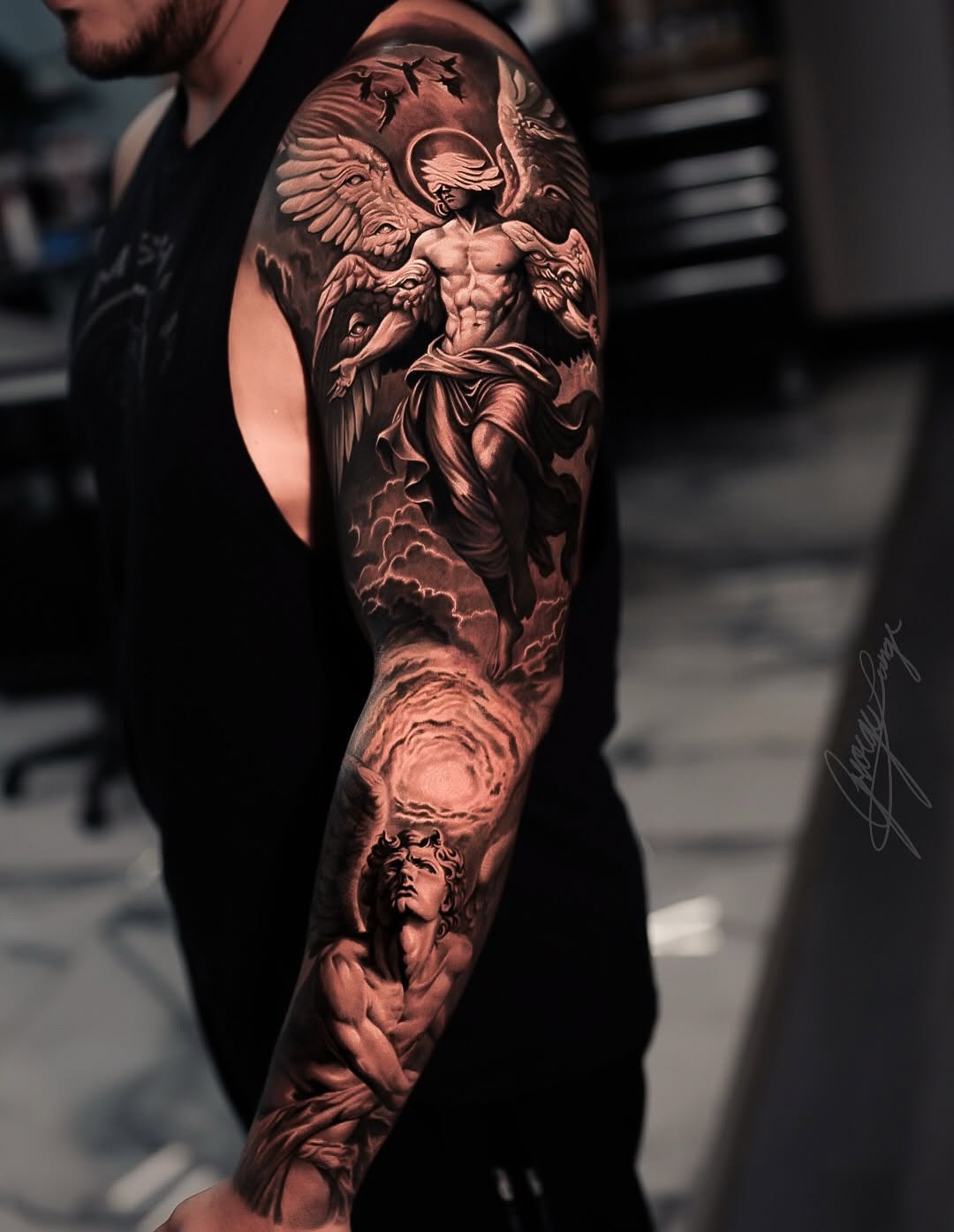 Angelic figures and clouds realism tattoo on the upper arm by George Lange