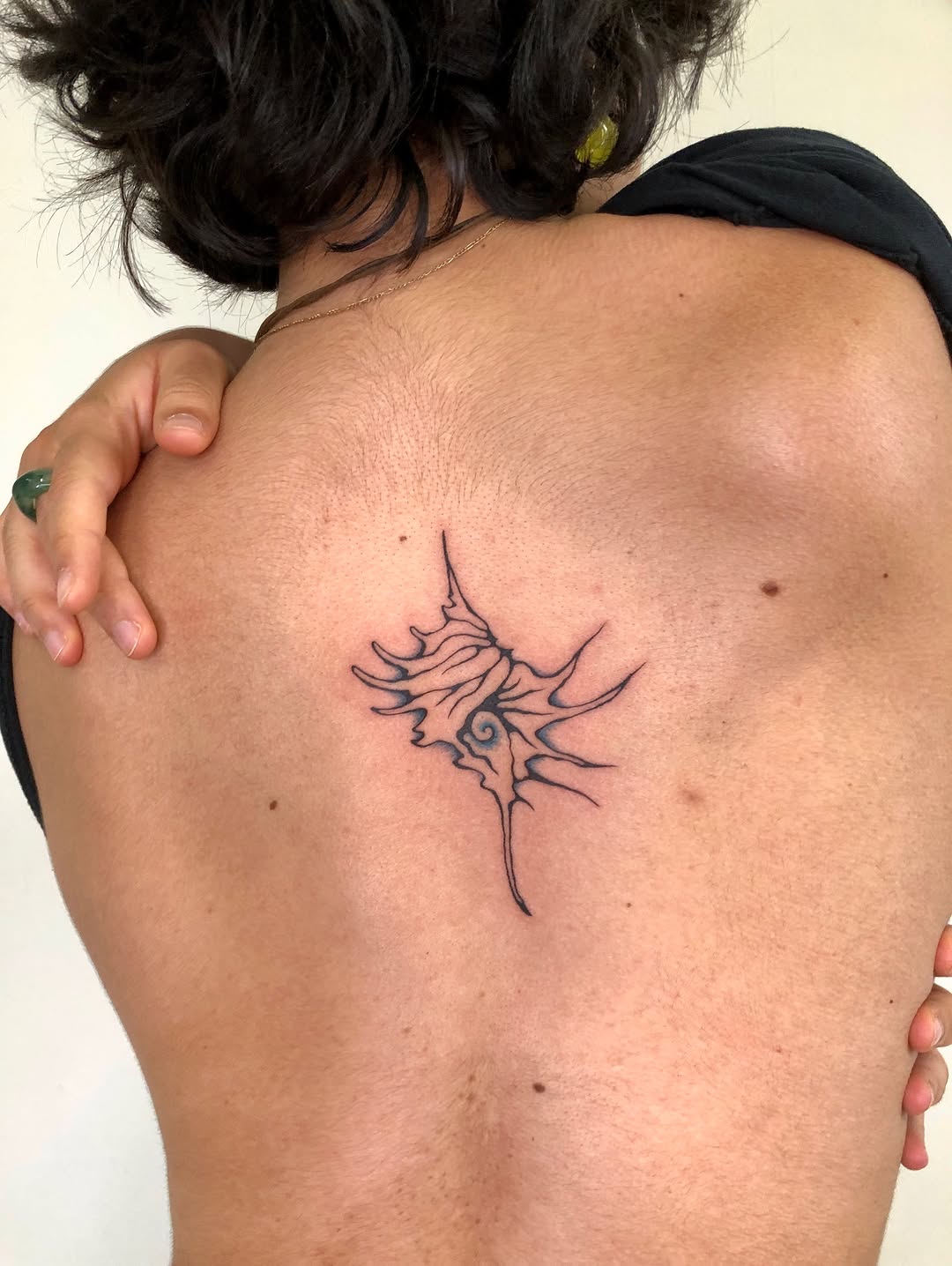 Abstract shell blackwork tattoo on the back by thalia