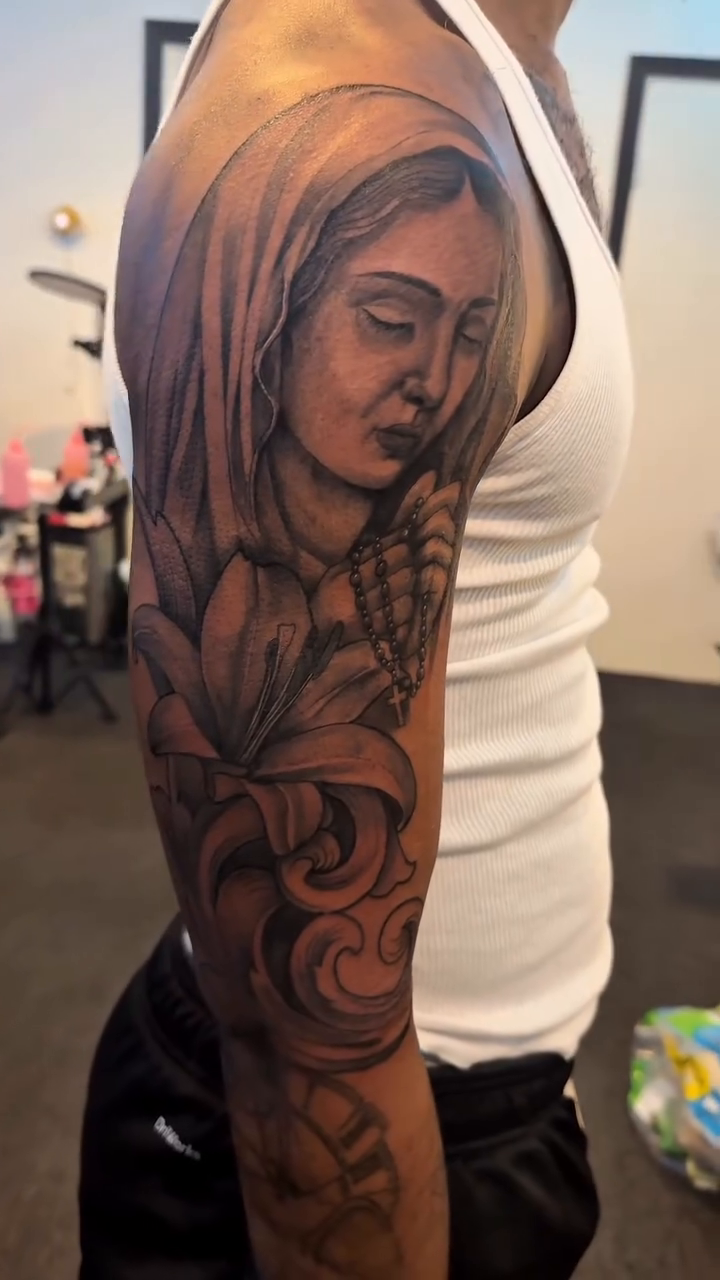 Virgin Mary with floral elements Chicano tattoo on the upper arm by 2realink - Tattoo Artist