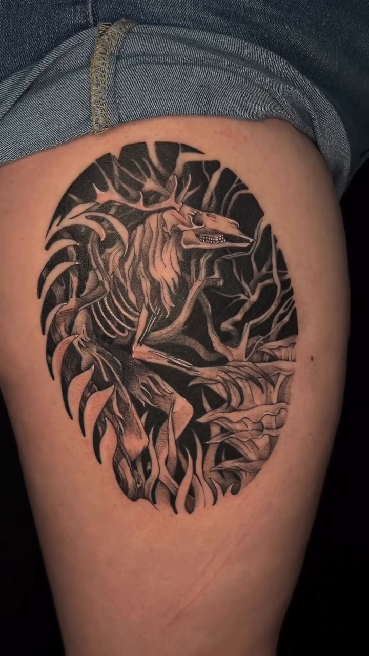 A skeletal raven with flames dark art tattoo on the thigh by Kait