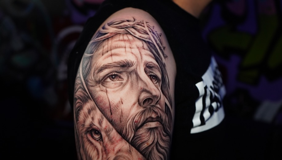 Jesus and lion Chicano tattoo on the upper arm by Abel Ponce