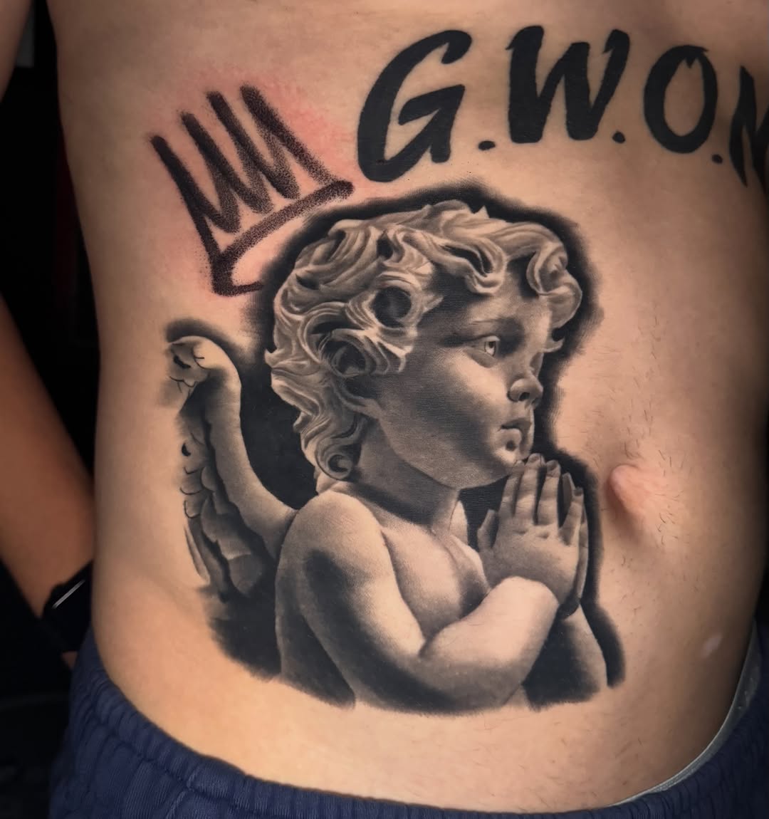 Cherub with praying hands and lettering realism tattoo on the ribs by Kaleb Trujillo