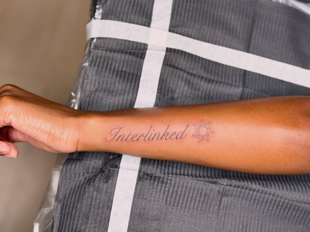 Interlinked text with sun symbol lettering tattoo on the forearm by Fineline Tattoos π€ Hailey L.