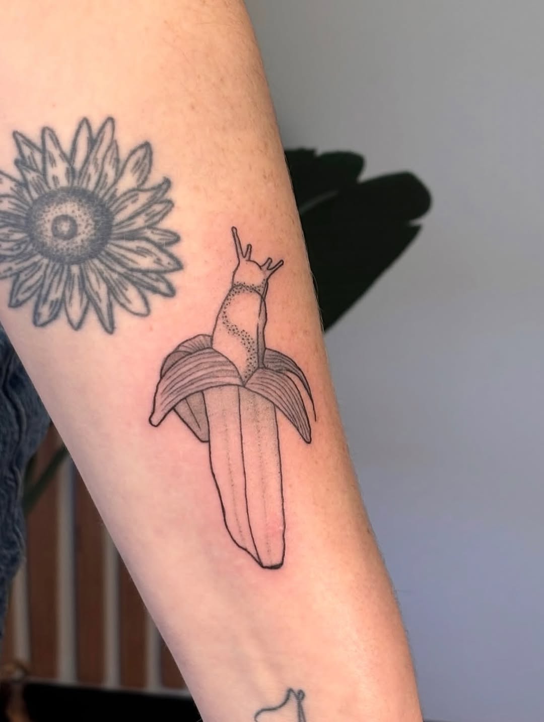Slug on banana surrealism tattoo on the forearm by Maddie