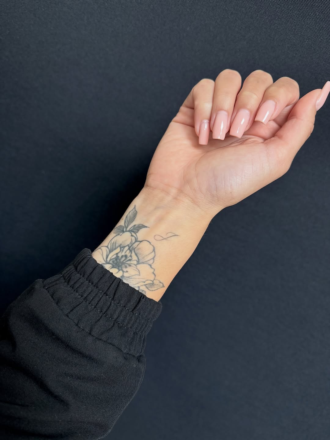 Flower and infinity symbol fine line tattoo on the forearm by Ava De La Torre
