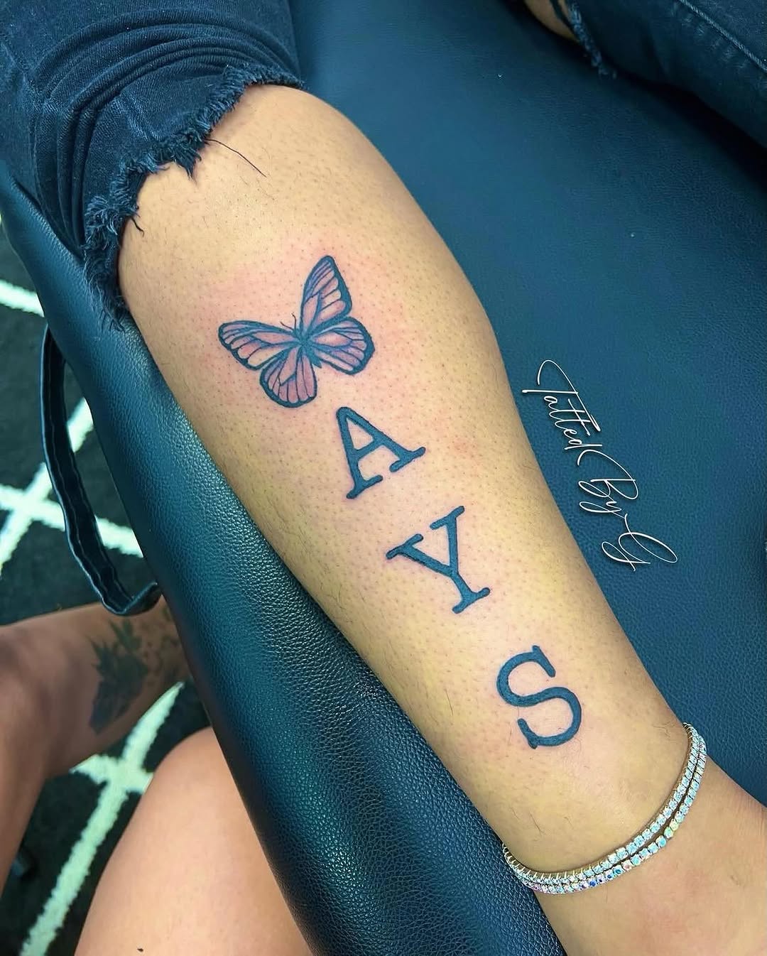 Butterfly and letters fine line tattoo on the forearm by Dallas Tattoo Artist