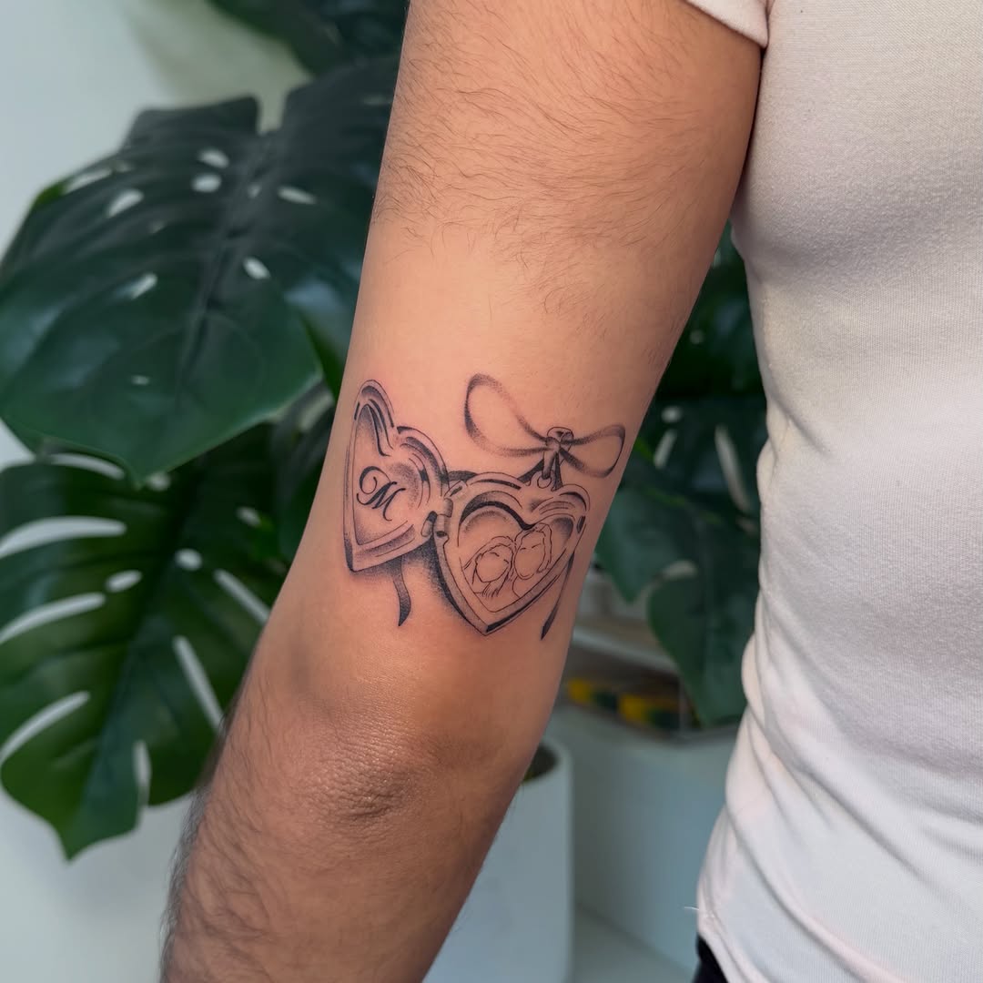 Heart locket with portraits fine line tattoo on the forearm by David