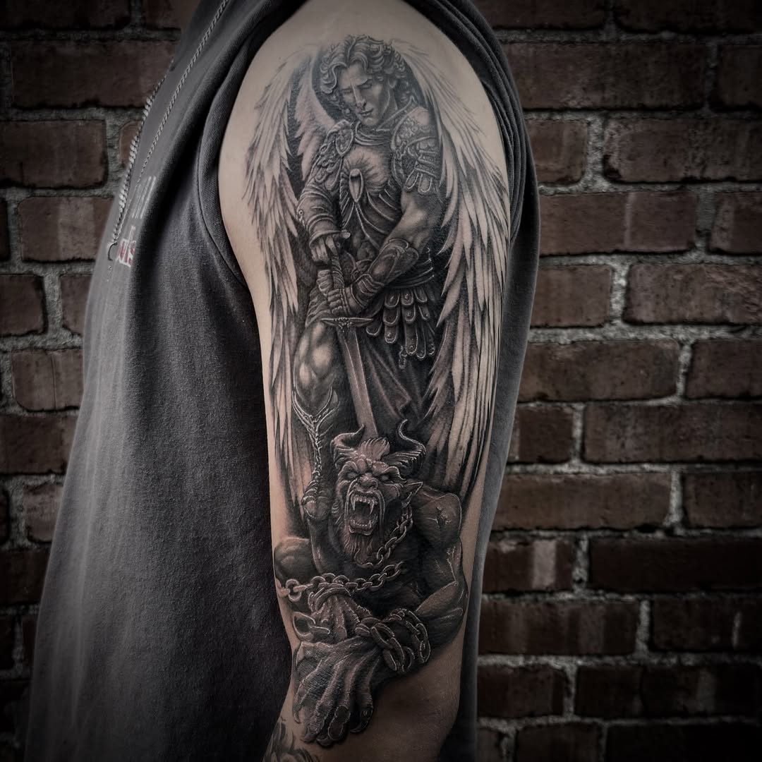 Angel fighting demon realism tattoo on the upper arm by Blake Van Vleck