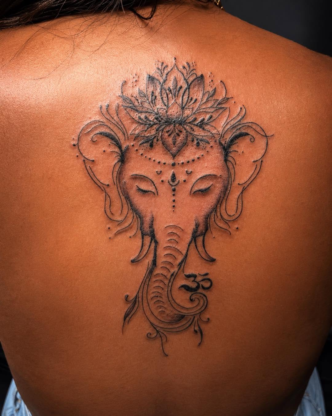 Ganesha with lotus and om symbol ornamental tattoo on the back by Flamboyant