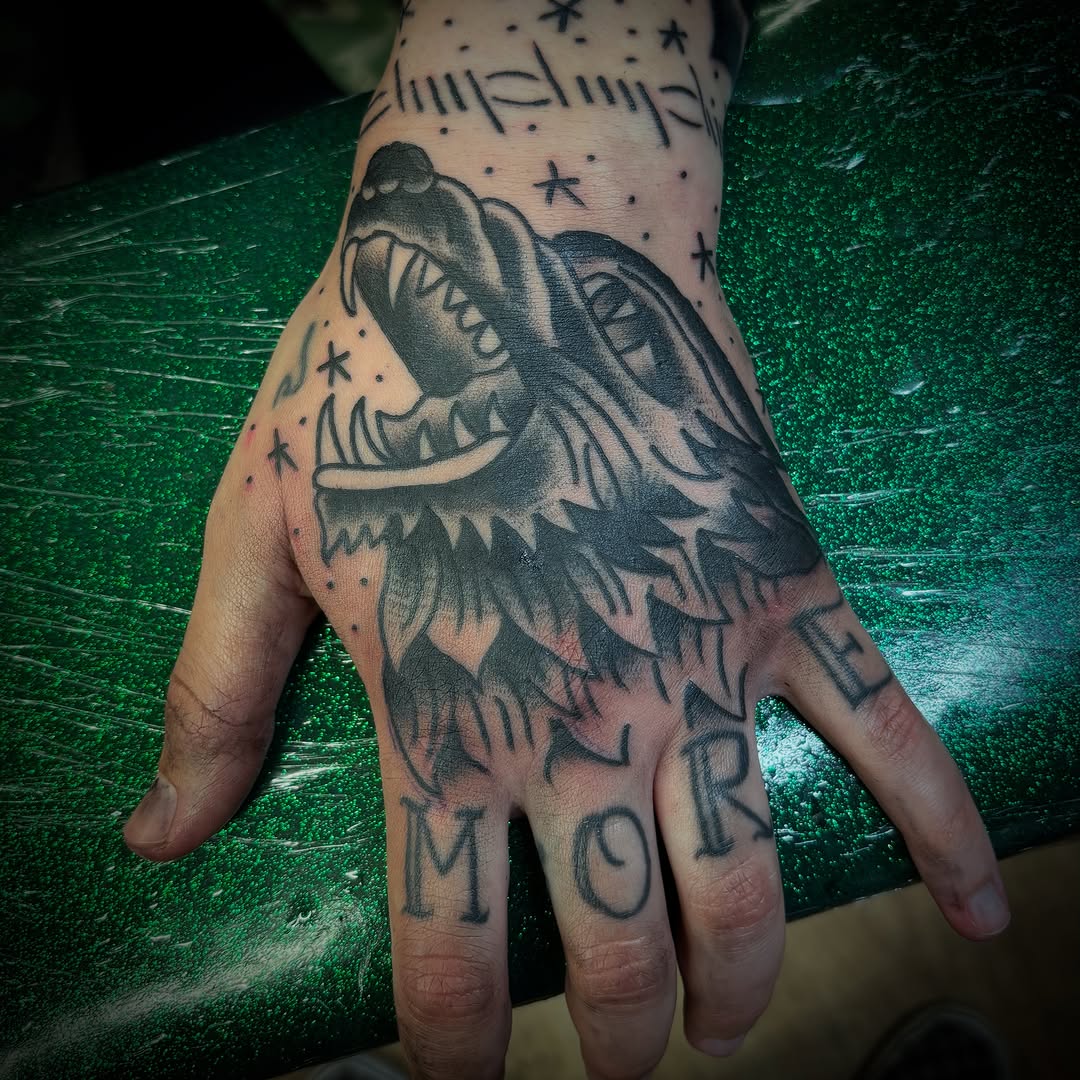 Wolf head and lettering tattoo on the hand by Tattoos Las Vegas,NV