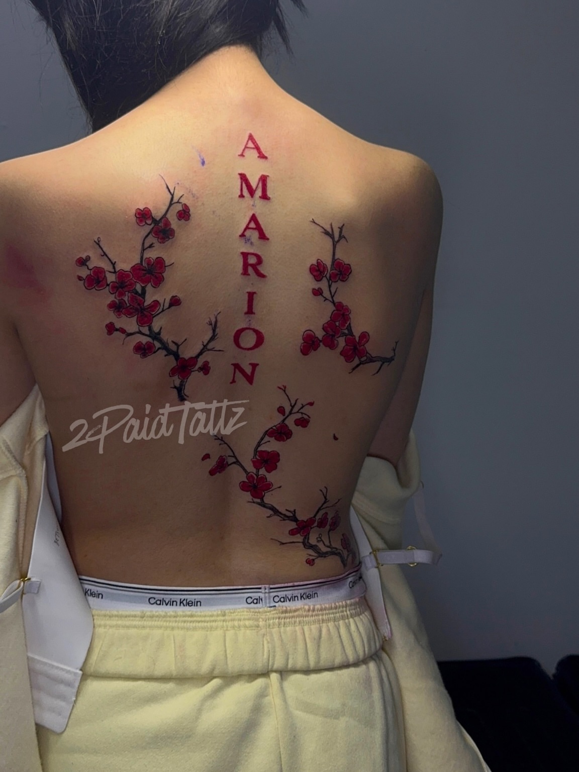 Cherry blossoms and name fine line tattoo on the back by 2PaidTattz