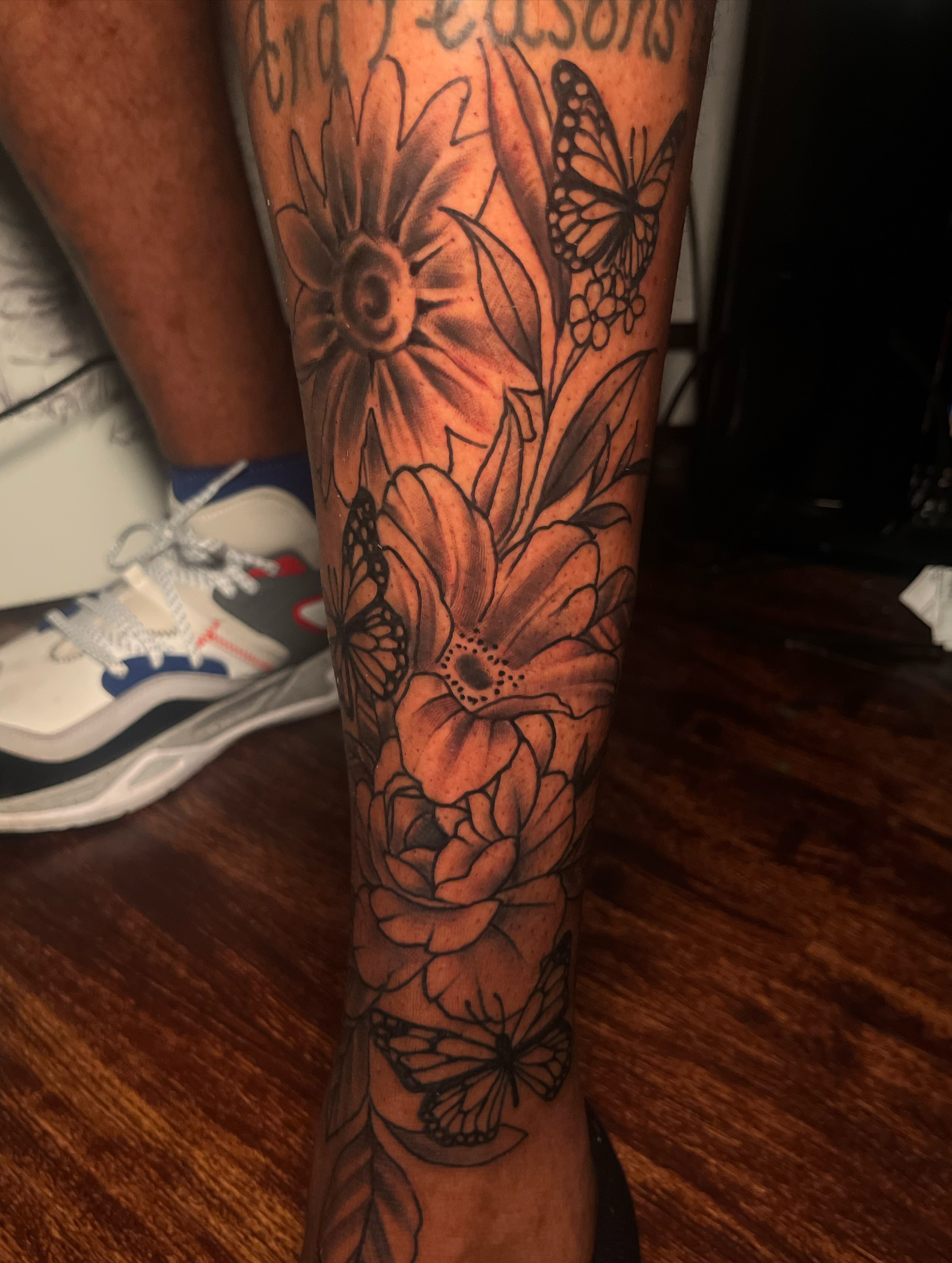 Flowers and butterflies black and grey tattoo on the calf by Darius Armour (Tattoo Artist)