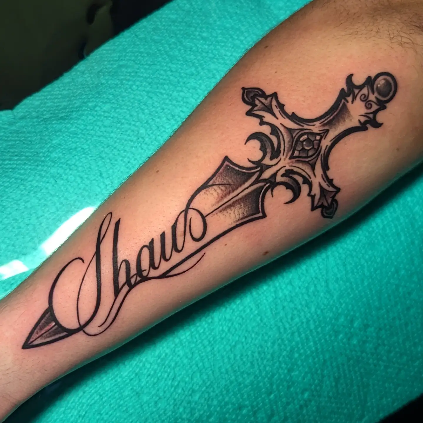 Cross with dagger black and grey tattoo on the forearm by 𝐈𝐚𝐧 𝐒𝐞𝐭𝐡 🕷️ Austin