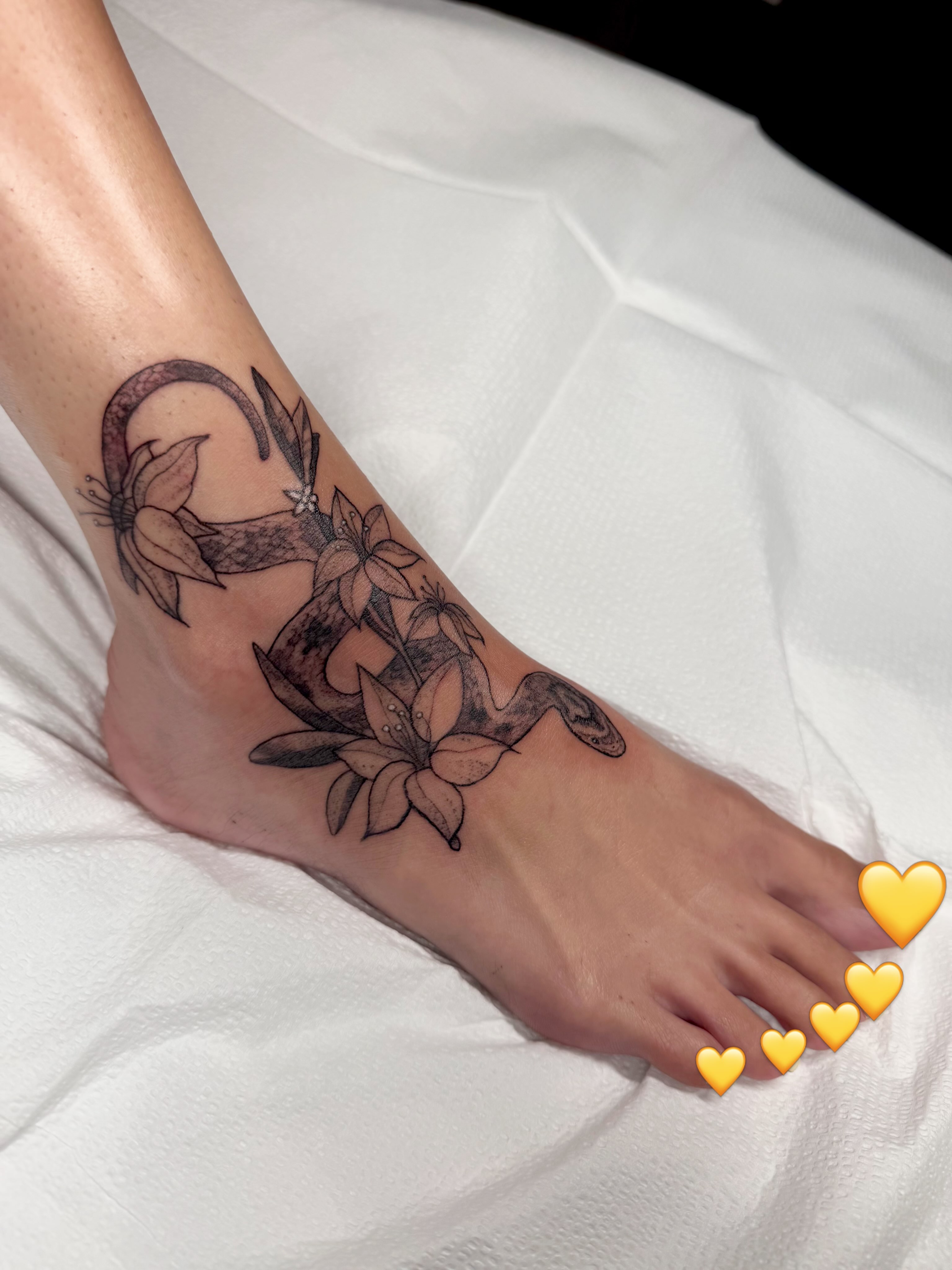 Snake and flowers black and grey tattoo on the foot by sarah bug