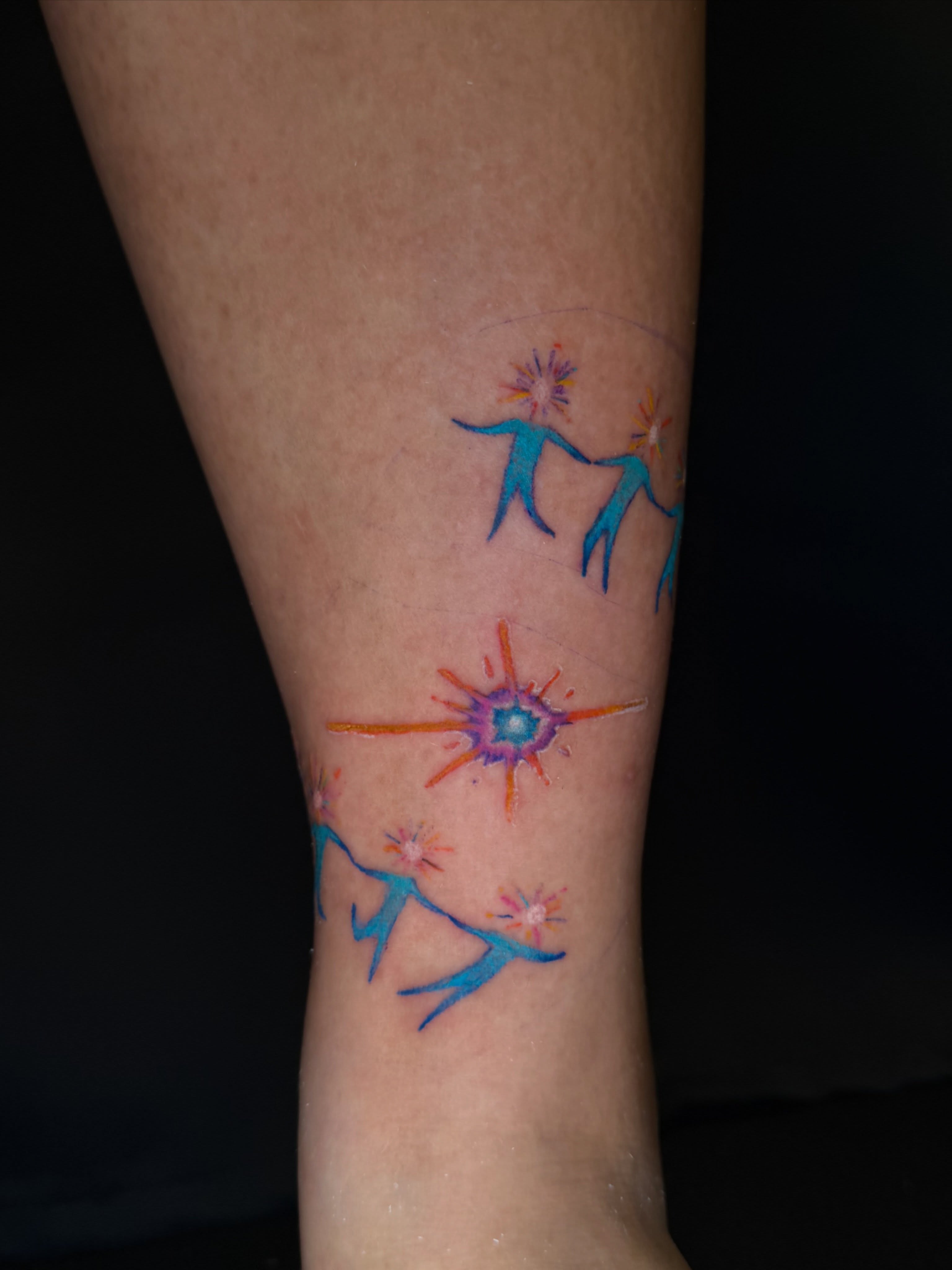 Dancers and starburst watercolor tattoo on the forearm by Hues 🦤 Clarksville Fine Line and Blackwork