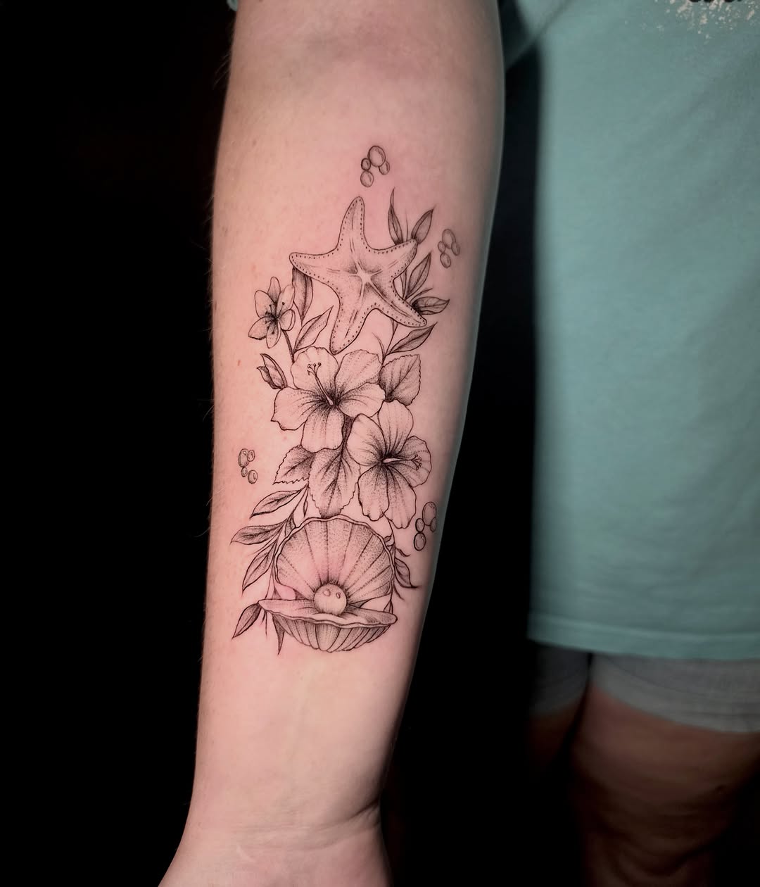 Sea-themed floral arrangement realism tattoo on the forearm by Scar